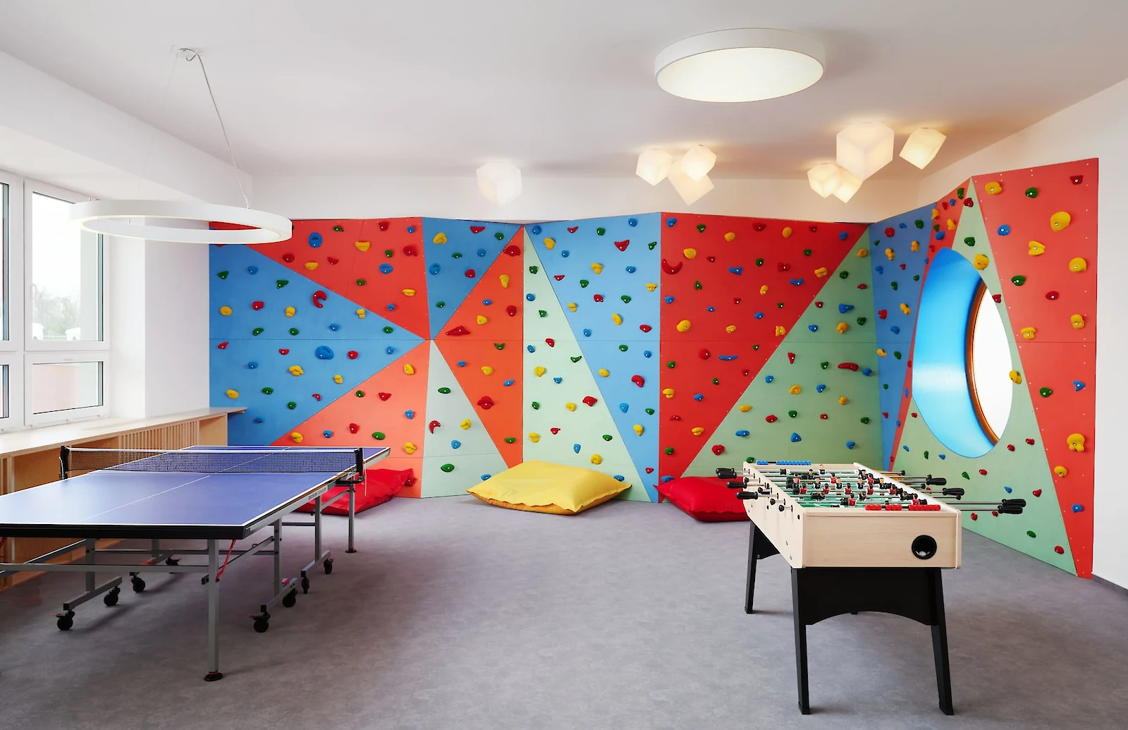 Družina - Místnost s dětskou boulder stěnou, ping-pongovým stolem a stolním fotbalem
