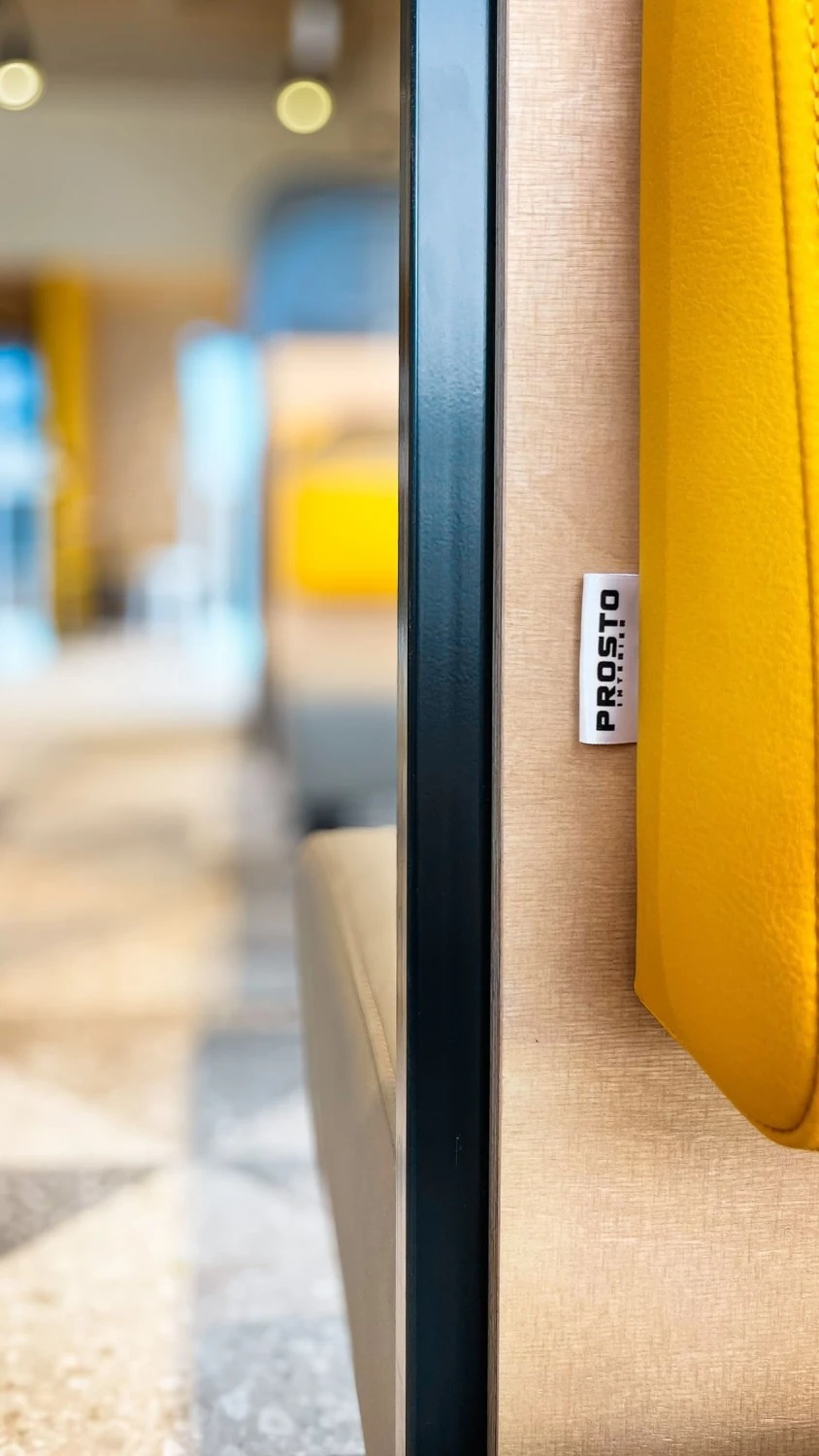 Detail stolu s kelímkem a žlutou židlí, v pozadí interiér restaurace