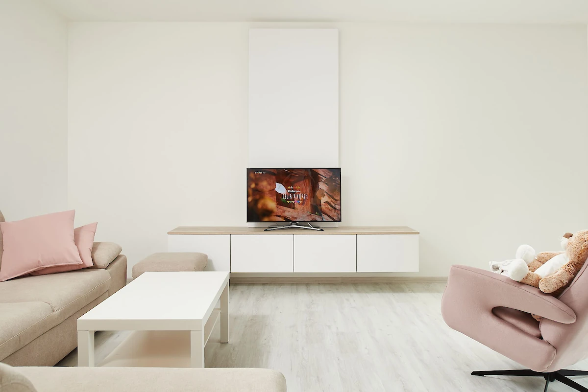 Interiér obýváku s pohovkou, křeslem a skříňkou s televizí