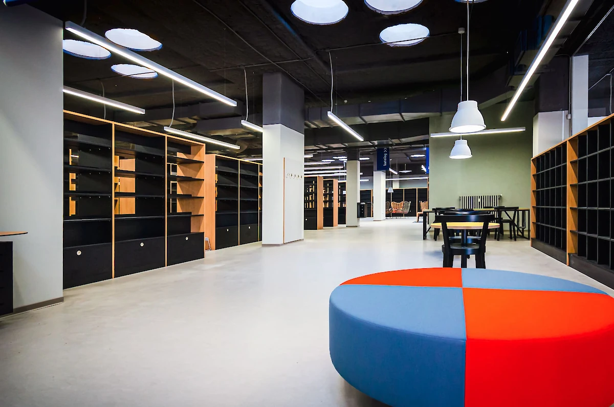 Knihovna s velkou barevnou kulatou lavicí v popředí